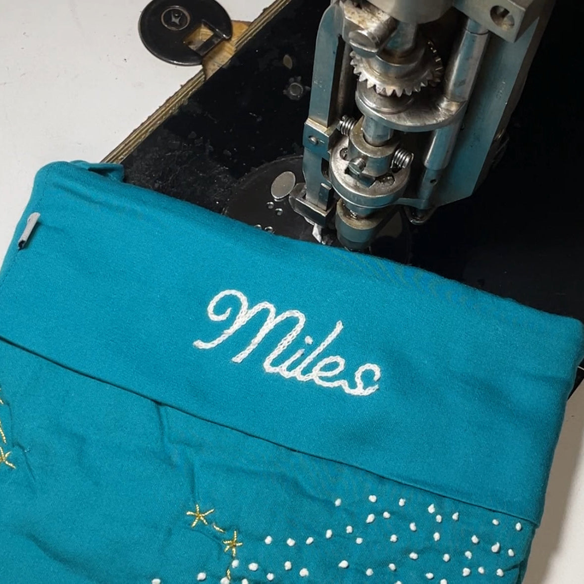 A teal stocking with Miles chainstitched