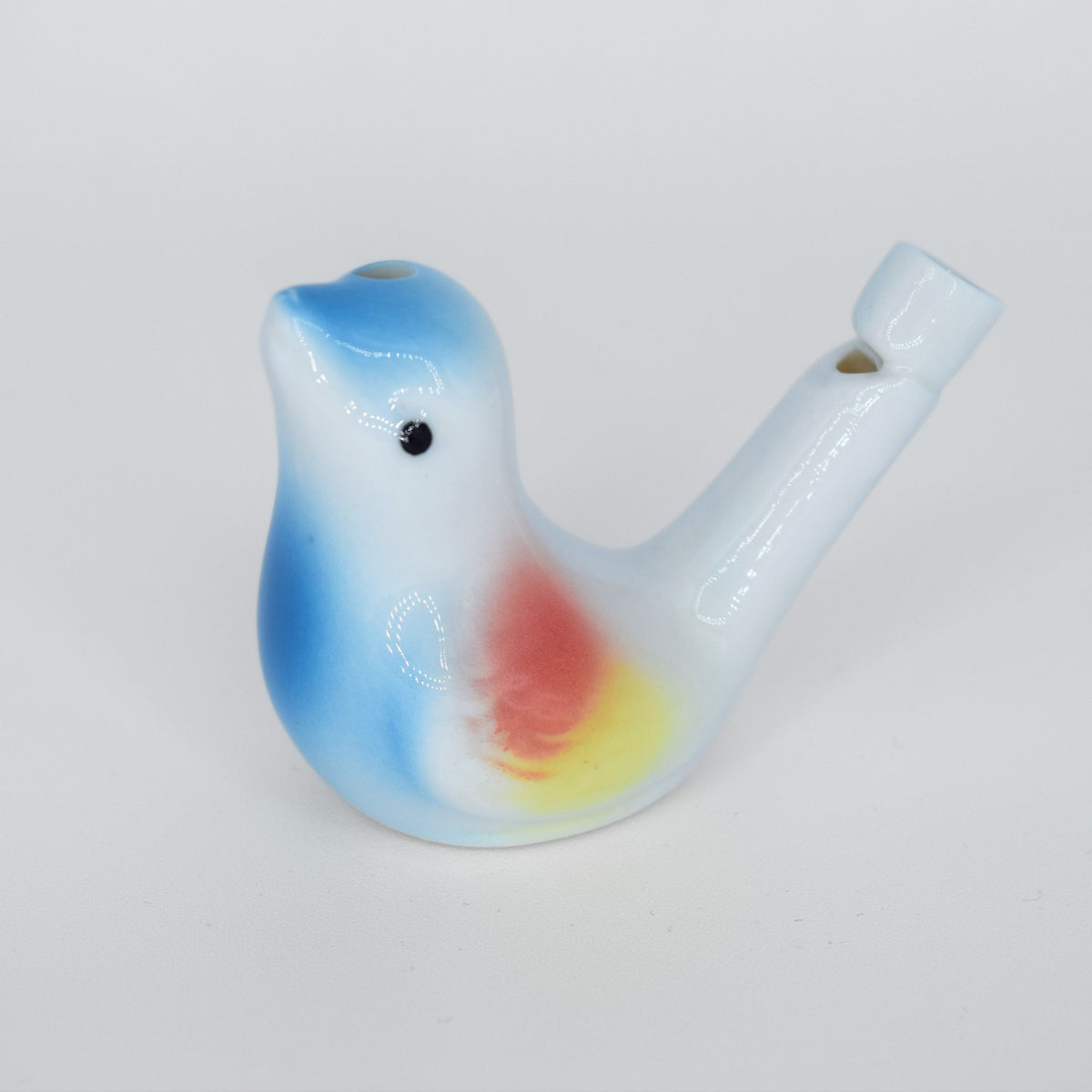 Porcelain water whisle shaped like a bird with a gradient color pattern on a white background