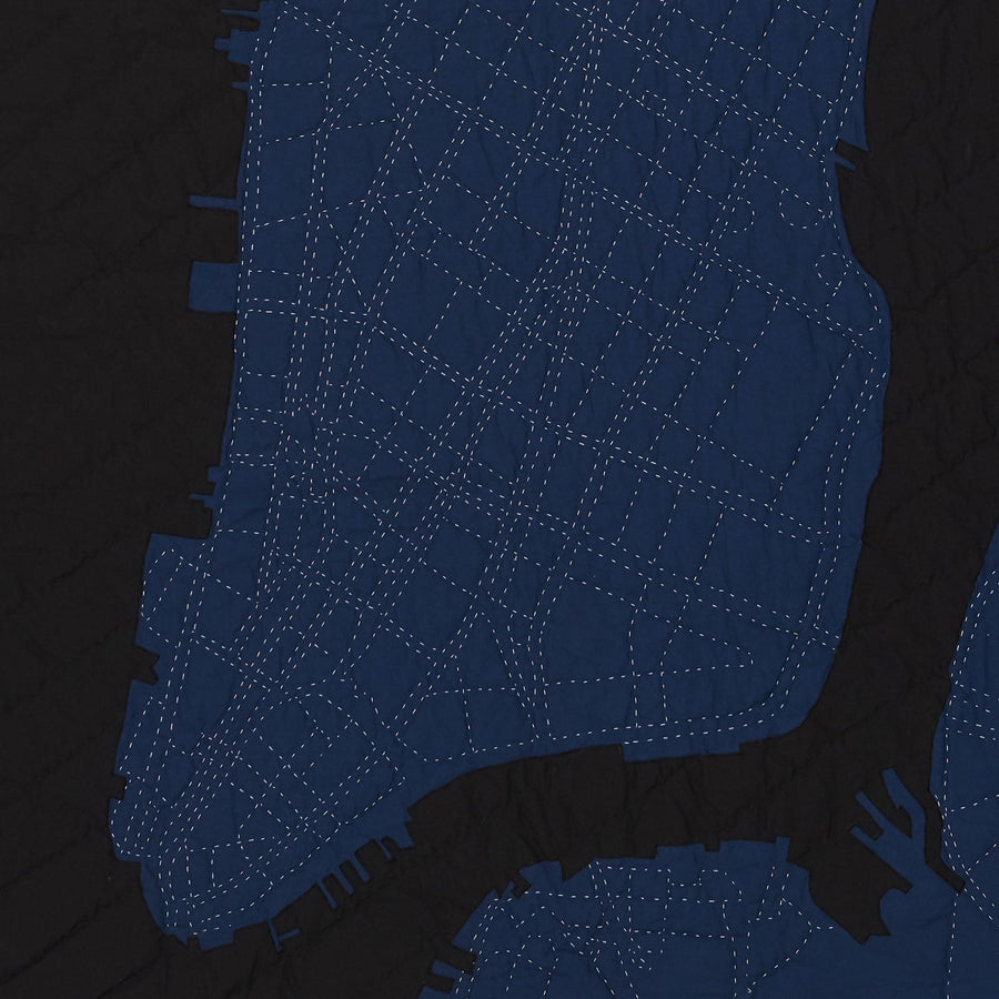 Detail of heirloom quilt, a hand-stitched map of New York City below 23rd Street with dark blue land and black water.