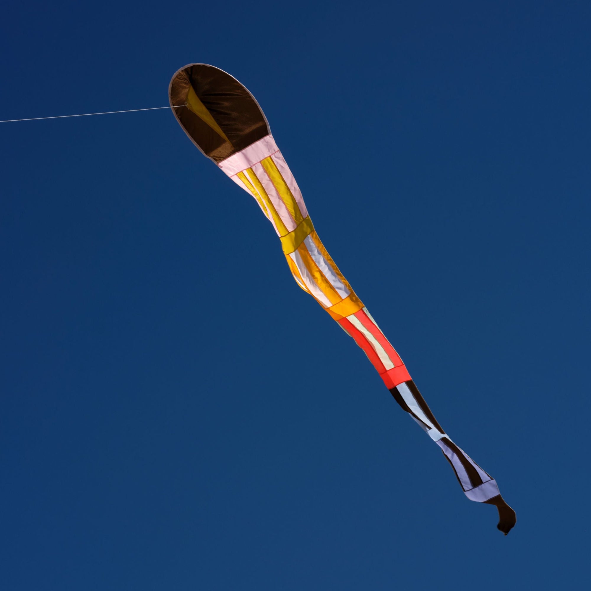 Striped comet kite flying in the sky_Haptic Lab