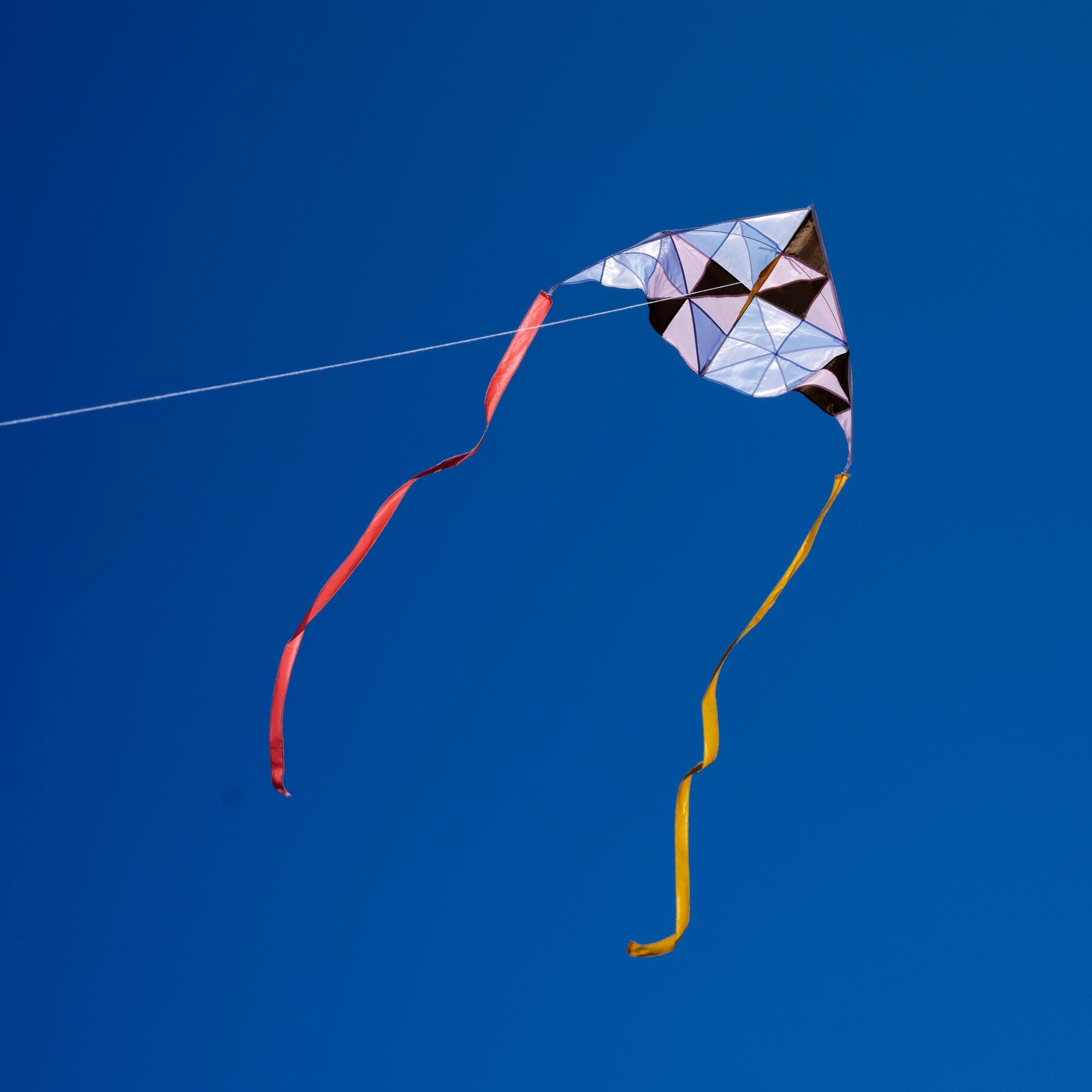Pinwheel patchwork delta kite flying in the blue sky_Haptic Lab
