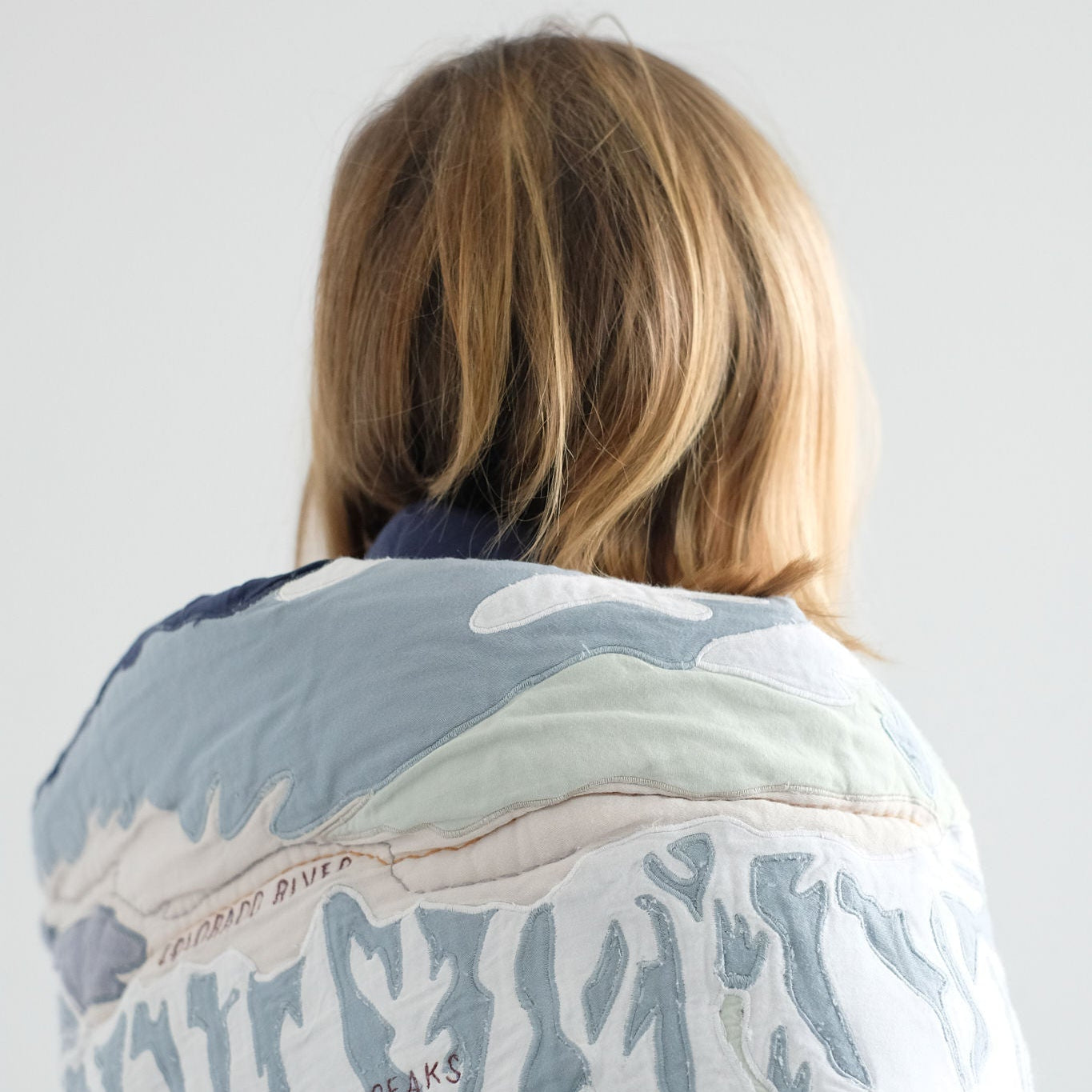 Person wrapped in a Front Range Quilt with a white background