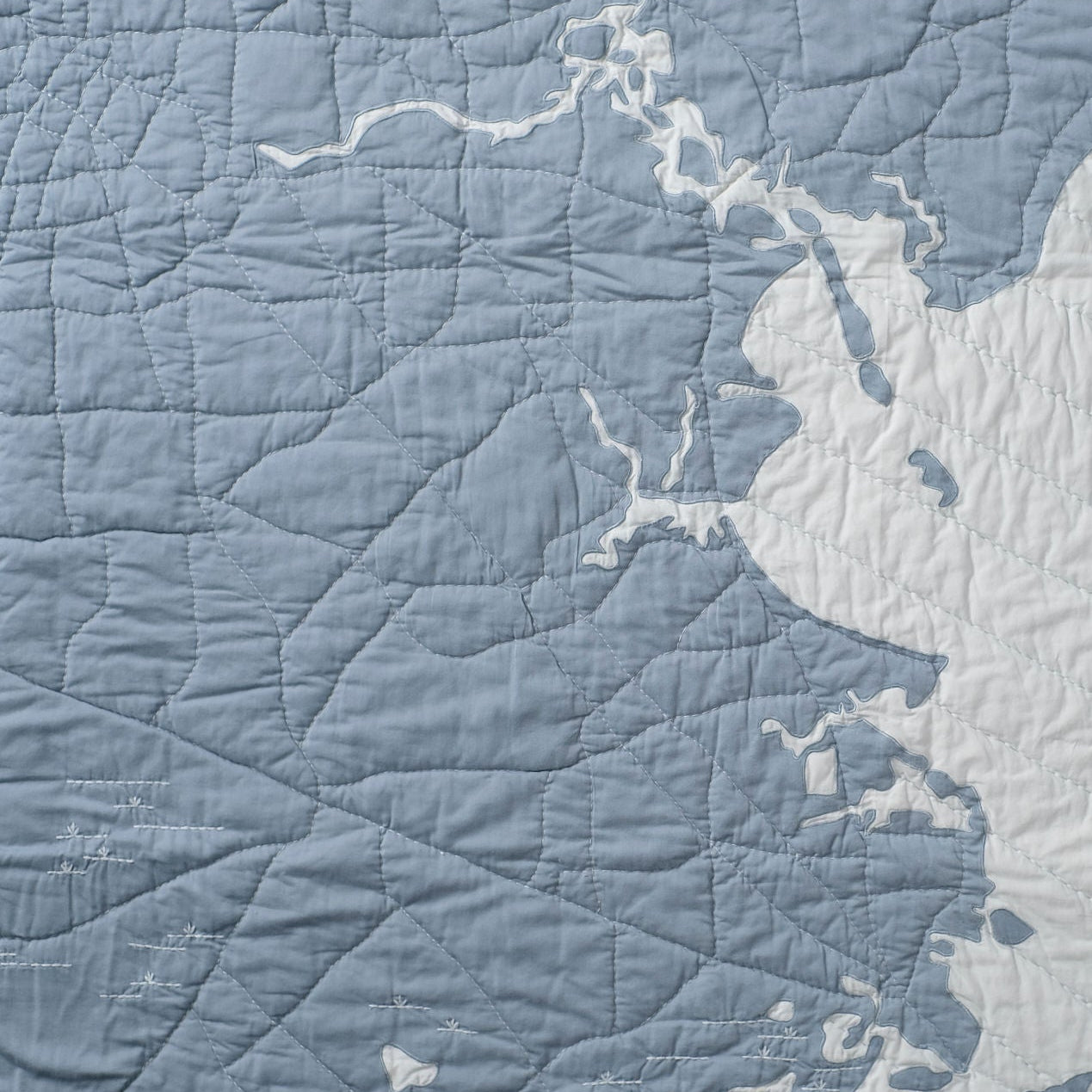 Close up of the hand quilting on a steel blue and light blue Houston Quilt