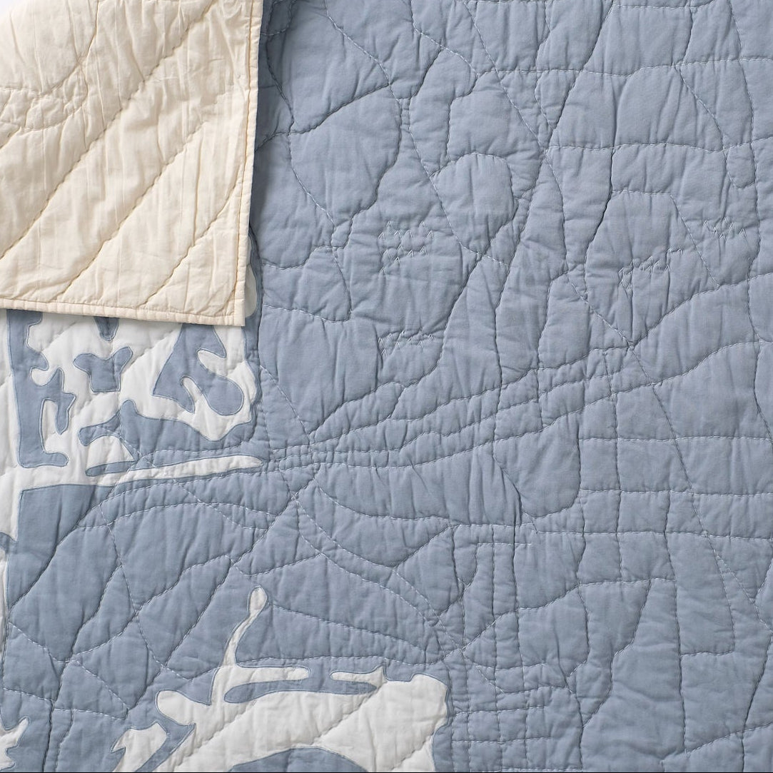 Steel blue and light blue hand quilted San Diego map quilt with a corner pulled down to see the ivory side