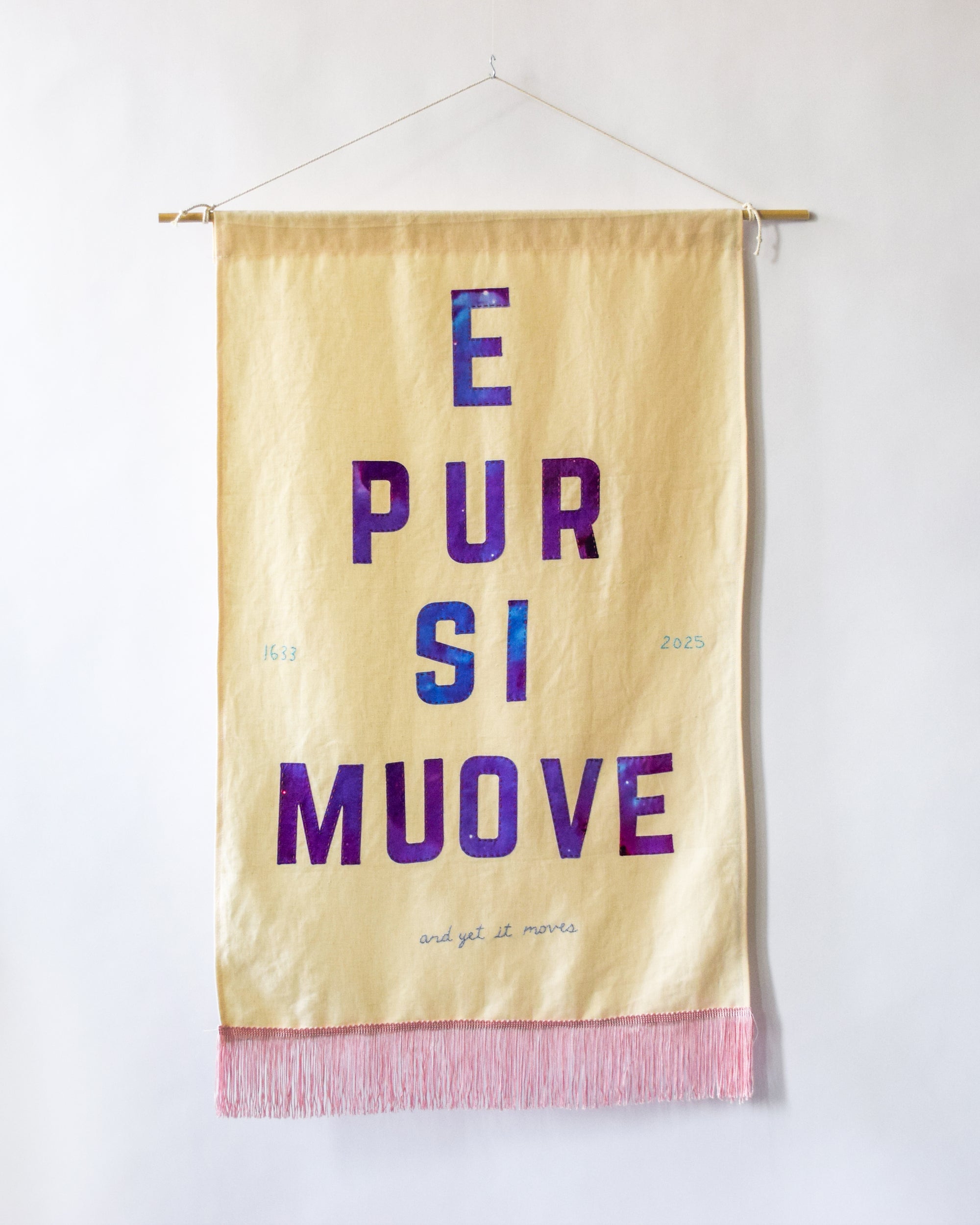 Textile banner with 'E Pur Si Muove' text on a linen background
