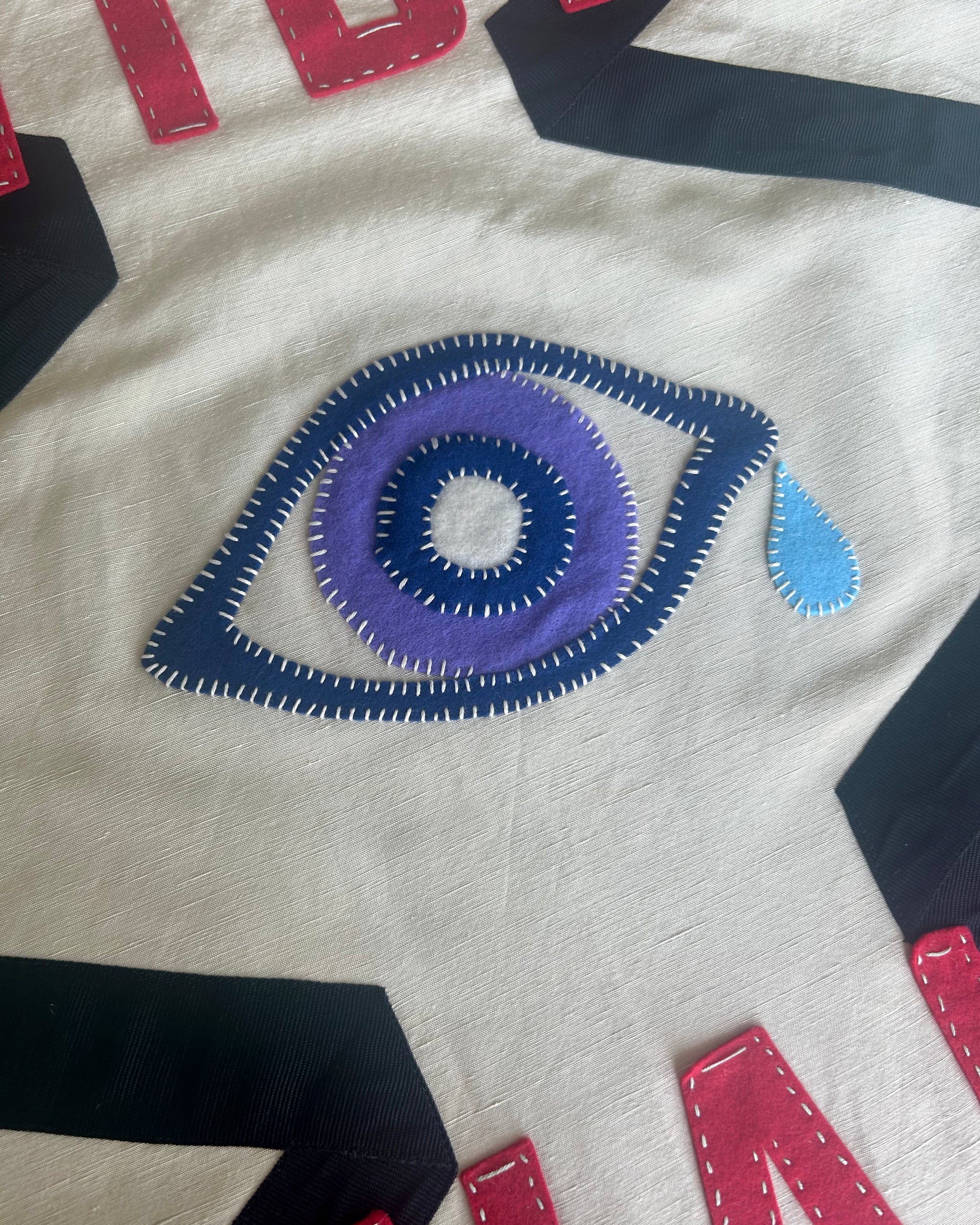 Close-up of banner with a large embroidered eye design on a white background