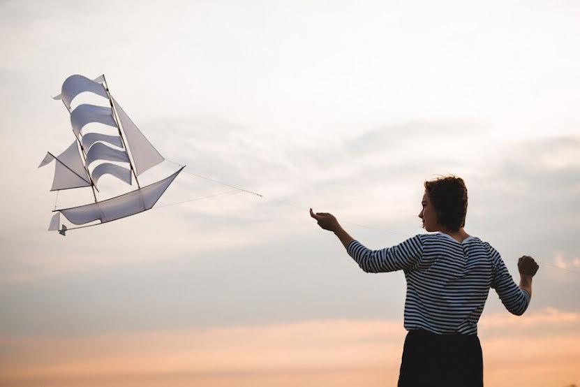 The classic Sailing Ship Kite by Haptic Lab really flies and doubles as a baby mobile, shown flying in a dreamy sunset.