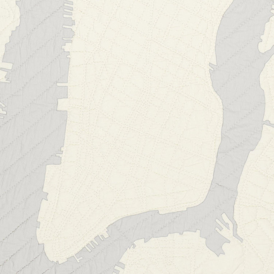Detail of heirloom quilt, a hand-stitched map of New York City below 23rd Street with ivory land and gray water.