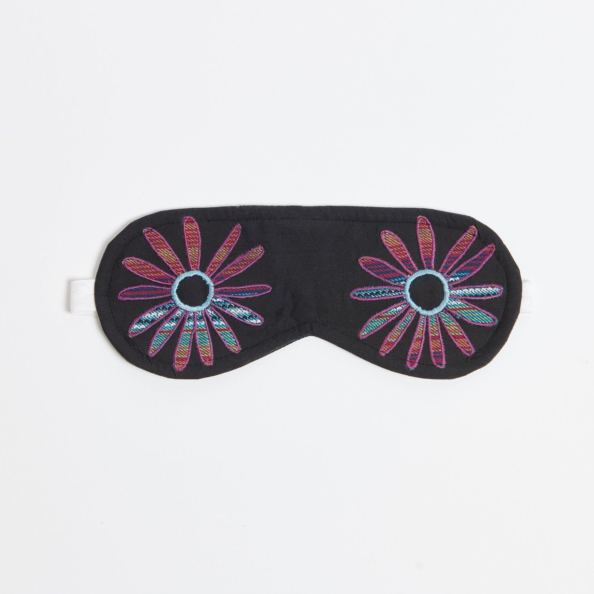 Eye mask on white background. Flower eyes appliqued with  a woven purple blue green fabric. 
