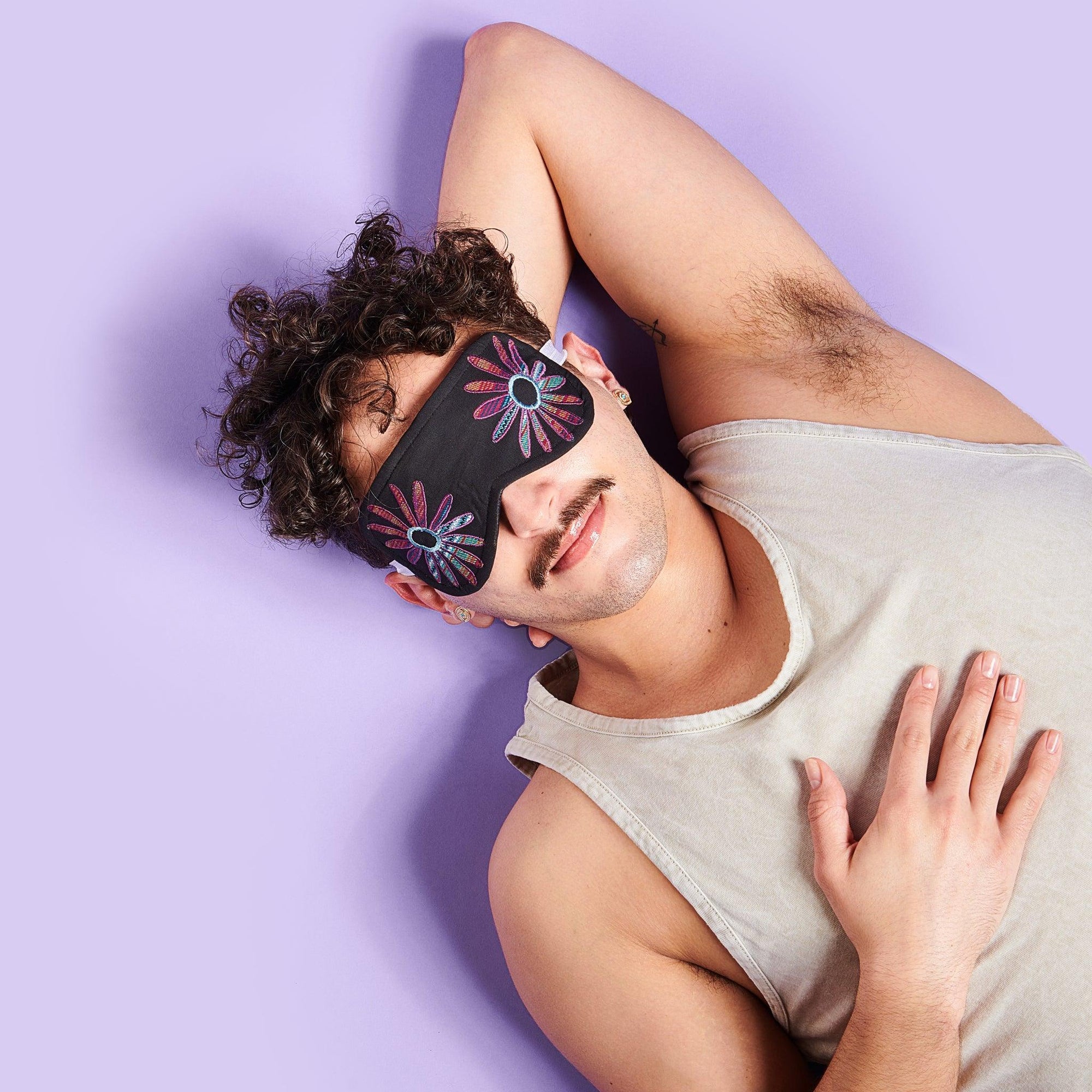 Flower eye mask on a person lying down on a purple background
