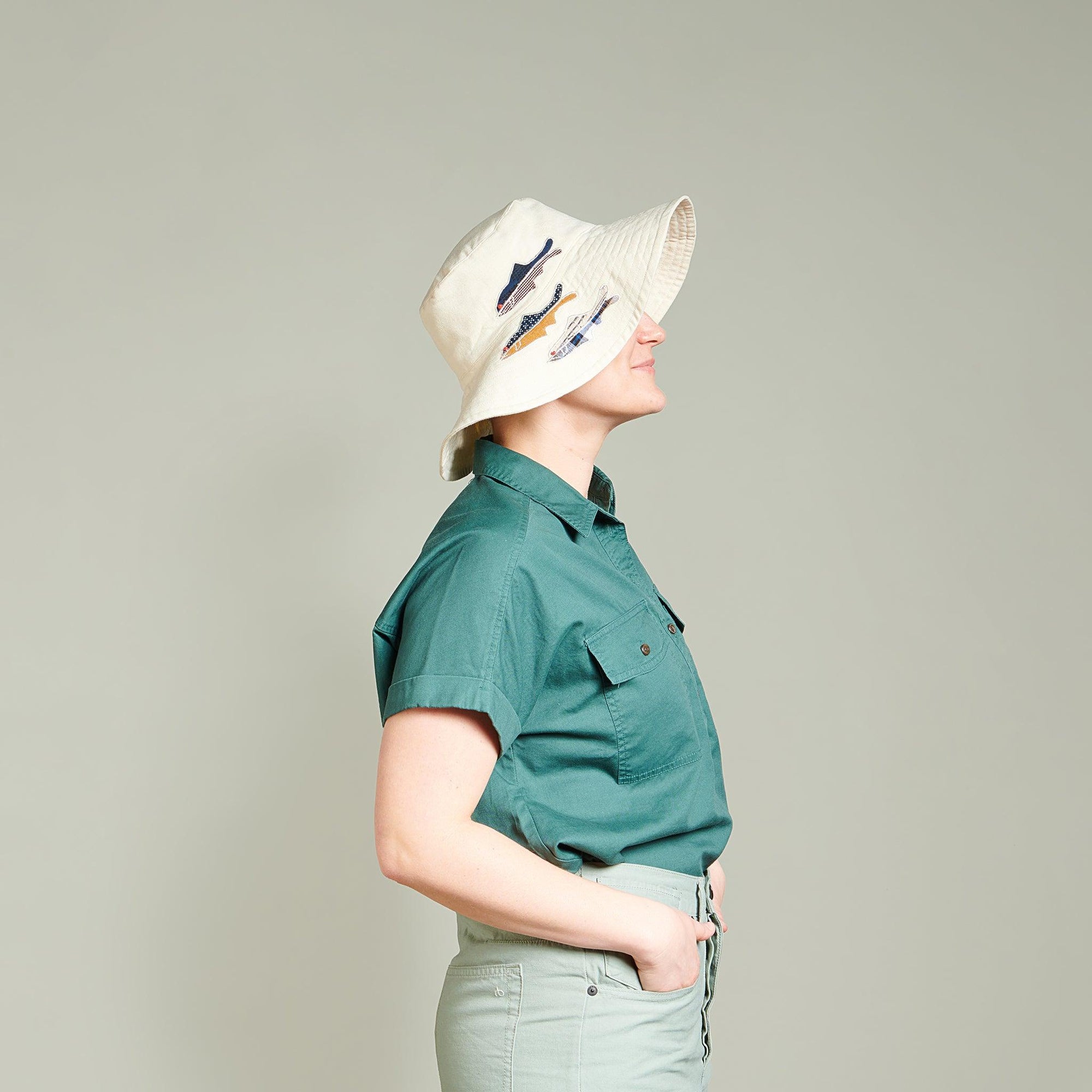 Side profile of person wearing the Ivory Sun Hat with appliquéd fish. 