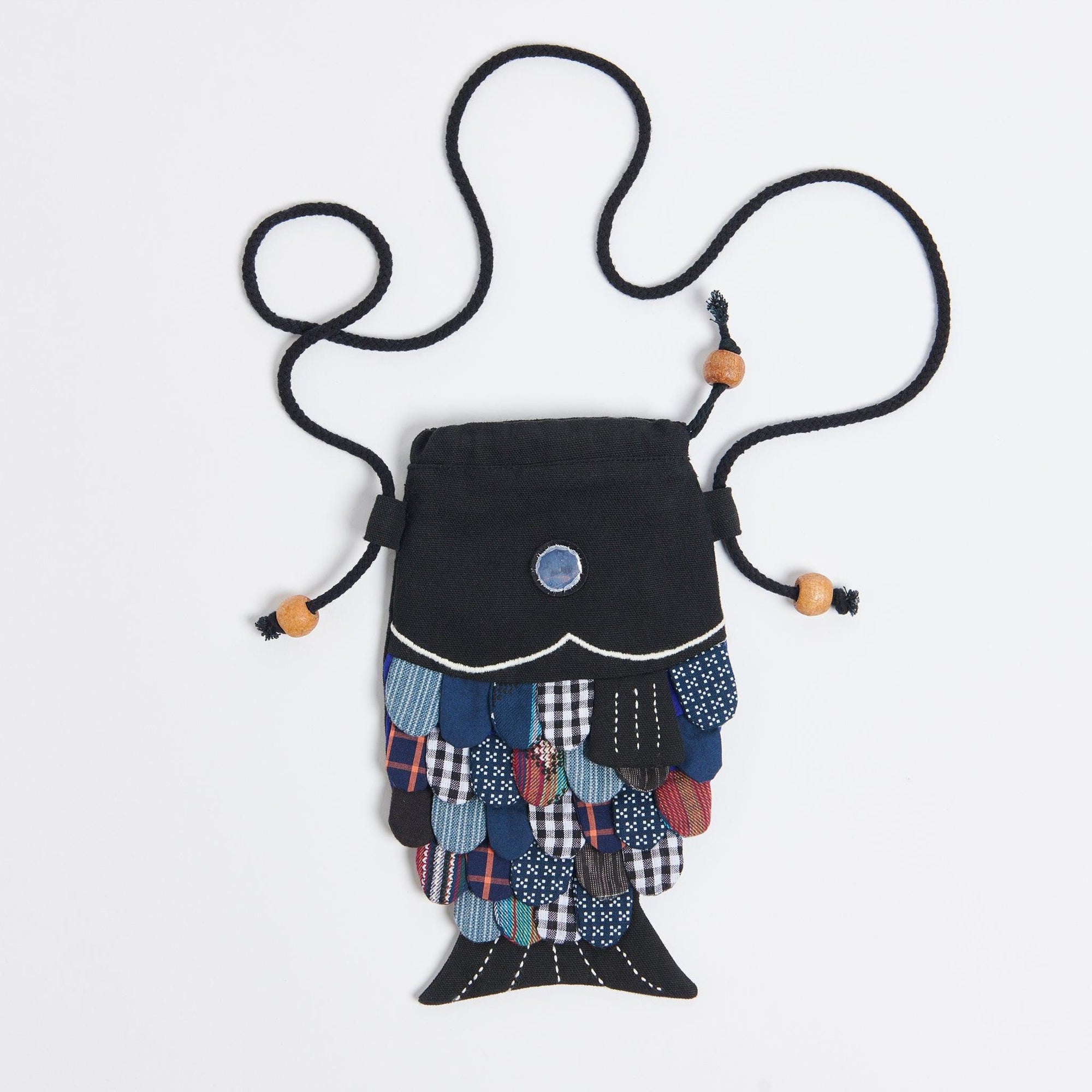Black fish purse. It has a metallic eye and the scales are made up of deadstock fabrics. 