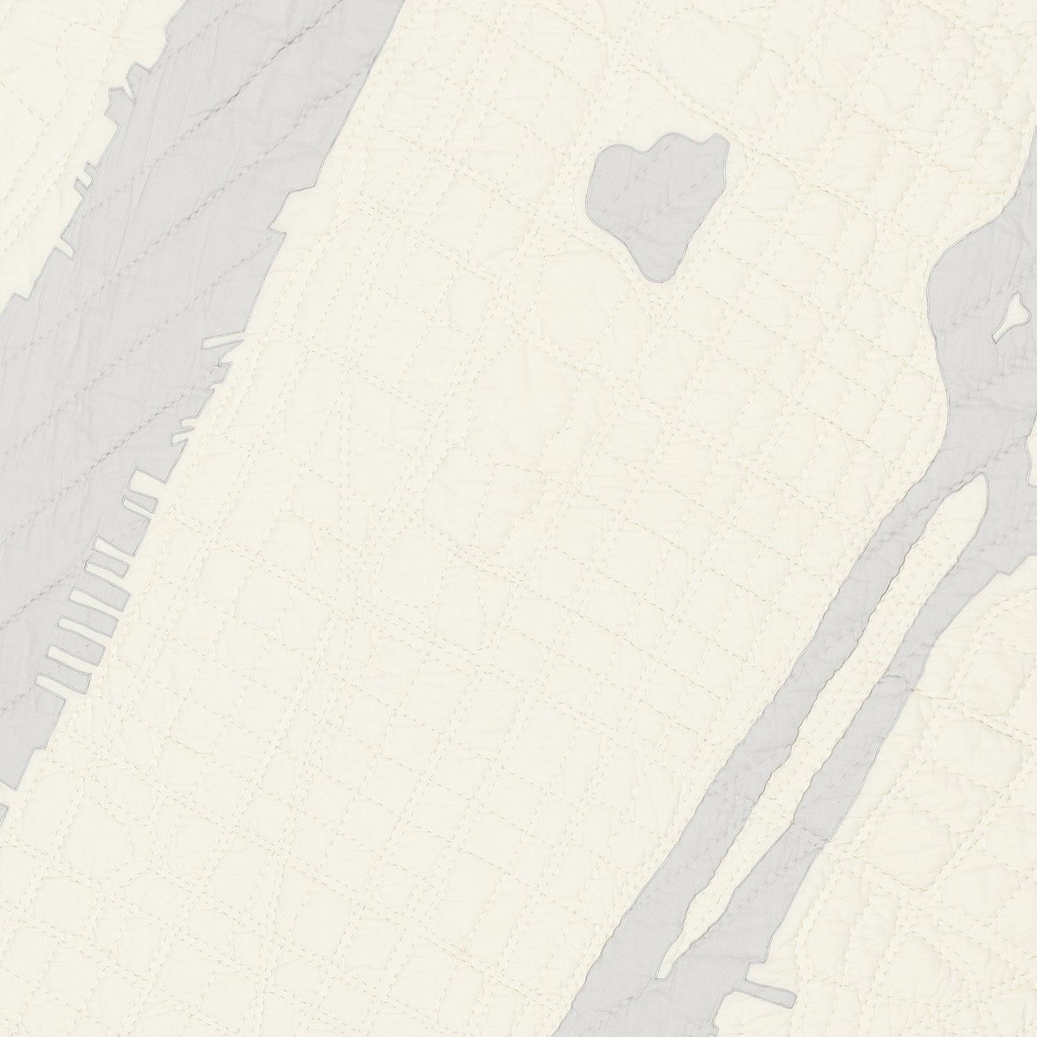 Detail of heirloom quilt, a hand-stitched map of New York City's Central Park reservoir, Hudson River, Roosevelt Island, East River, and surrounding streets with ivory land and gray water.